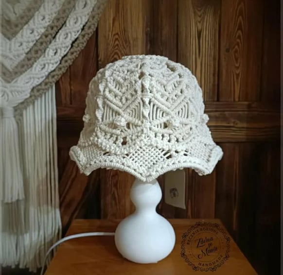 White crocheted lace hat displayed on a white mannequin head against wooden paneled wall background