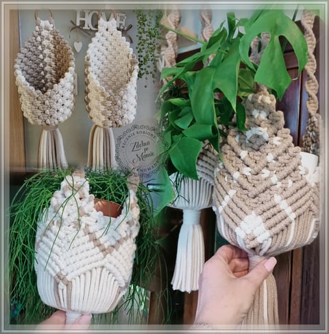 Handmade macramé plant hangers in cream and white with tassels, displayed with potted houseplants including trailing ivy and monstera